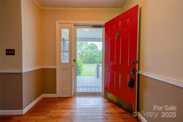 foyer featuring wood finished floors, crown molding, and baseboards