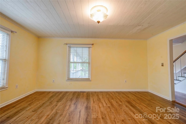 unfurnished room with stairway, crown molding, baseboards, and wood finished floors