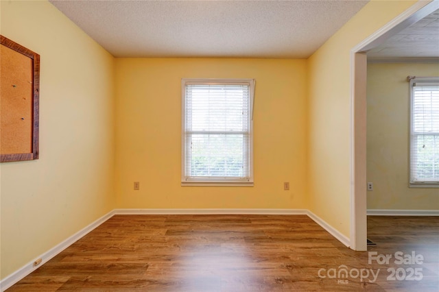 empty room with baseboards, wood finished floors, and a textured ceiling