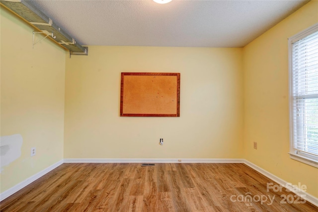 unfurnished room with wood finished floors, visible vents, and a healthy amount of sunlight