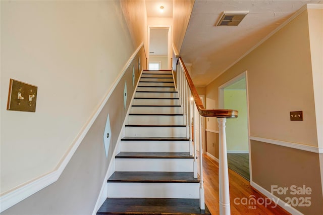 staircase with baseboards, ornamental molding, wood finished floors, and visible vents