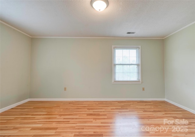 unfurnished room featuring a textured ceiling, light wood-type flooring, baseboards, visible vents, and ornamental molding