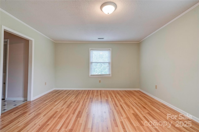 empty room with light wood-style flooring, a textured ceiling, crown molding, and baseboards