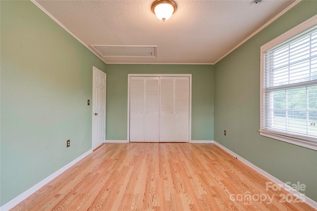 unfurnished bedroom featuring wood finished floors, a textured ceiling, a closet, and ornamental molding