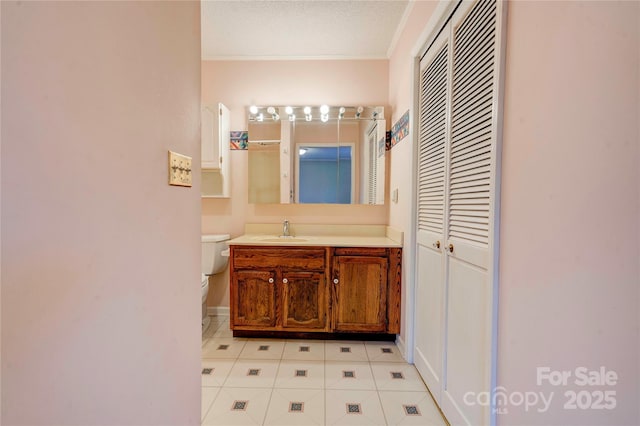 bathroom with tile patterned flooring, toilet, vanity, ornamental molding, and baseboards