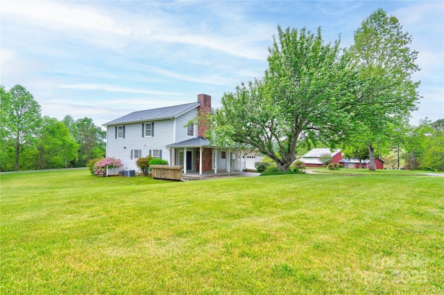 rear view of property featuring a chimney, a porch, and a lawn