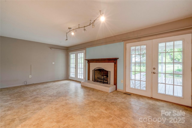 unfurnished living room with rail lighting, visible vents, french doors, baseboards, and a fireplace