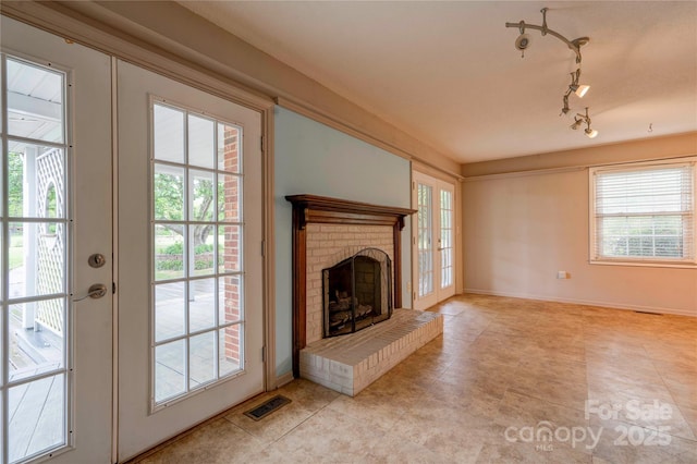unfurnished living room with a brick fireplace, visible vents, french doors, and a healthy amount of sunlight