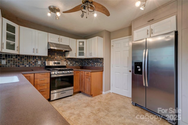 kitchen featuring decorative backsplash, glass insert cabinets, ceiling fan, appliances with stainless steel finishes, and under cabinet range hood