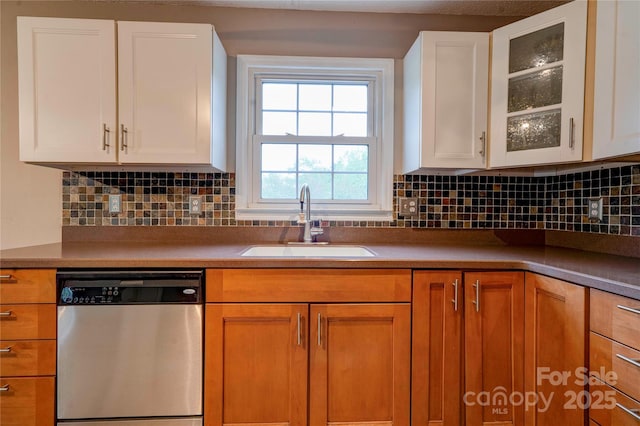 kitchen with dishwasher, a sink, decorative backsplash, glass insert cabinets, and white cabinetry