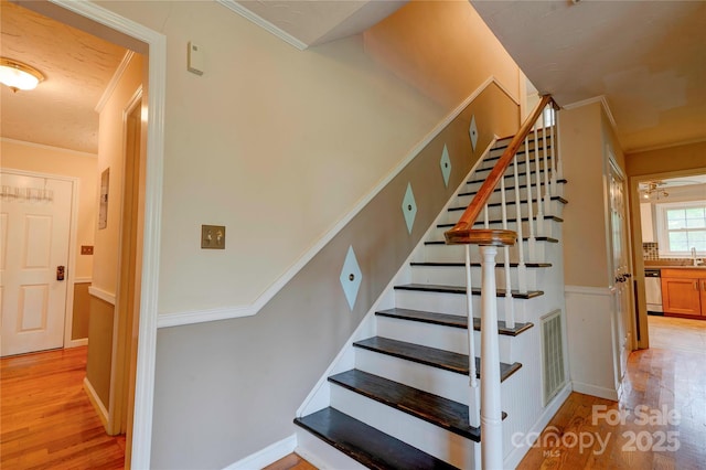 stairway featuring visible vents, wood finished floors, and crown molding