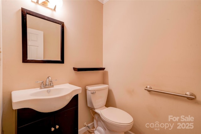 half bath featuring baseboards, vanity, and toilet
