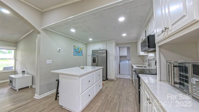 8140 Karriker Rd, Kannapolis, NC 28081 - kitchen with crown molding, washer / dryer, a sink, a center island, and stainless steel appliances