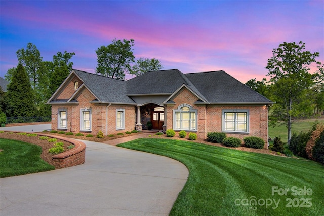 view of front facade with brick siding, a shingled roof, and a front yard
