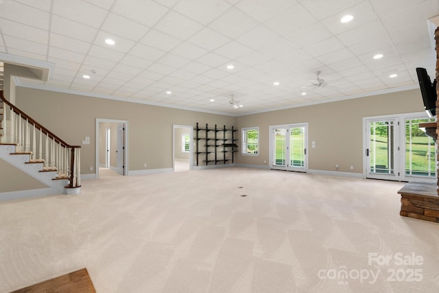 unfurnished living room with a ceiling fan, baseboards, carpet, and crown molding