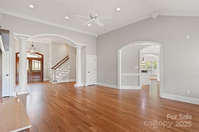 unfurnished living room featuring arched walkways, a ceiling fan, and wood finished floors