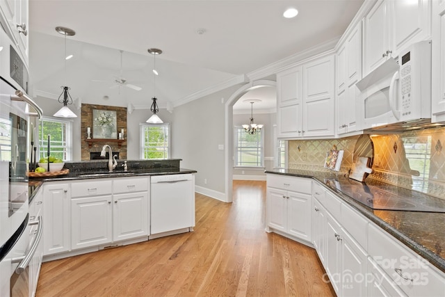 kitchen featuring light wood finished floors, arched walkways, a sink, ceiling fan with notable chandelier, and white appliances