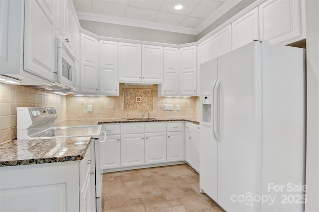 kitchen with dark stone counters, white cabinets, and white appliances