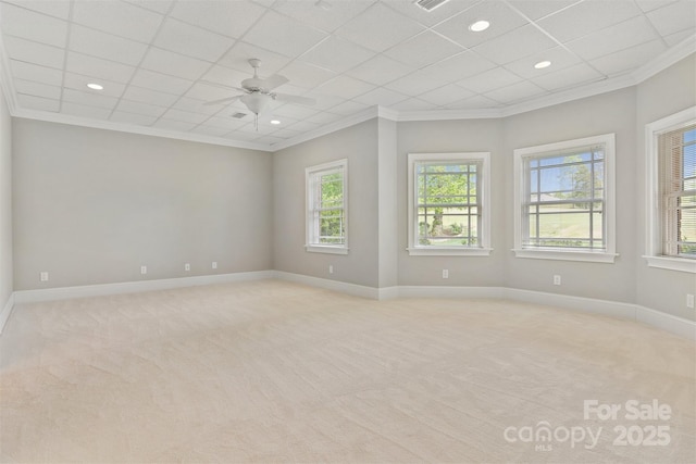 unfurnished room featuring ceiling fan, light carpet, baseboards, and ornamental molding