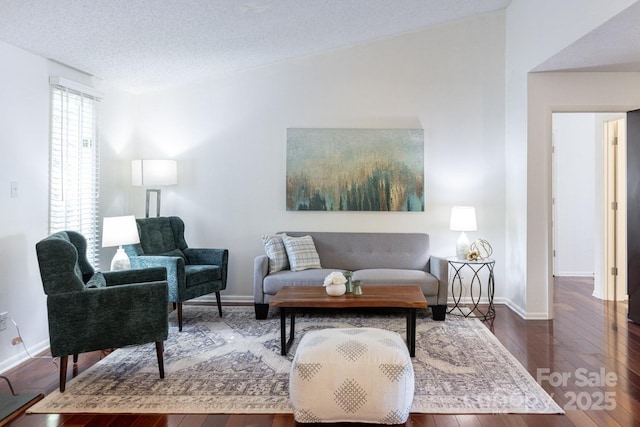 living room with a textured ceiling, hardwood / wood-style flooring, and baseboards