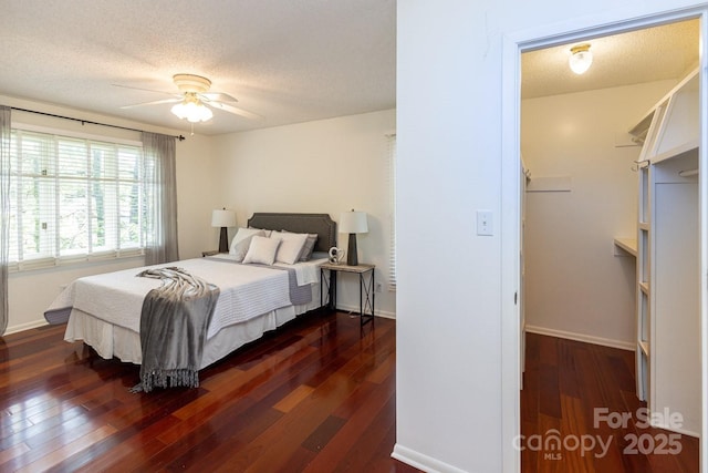 bedroom featuring dark wood-style floors, baseboards, ceiling fan, and a textured ceiling