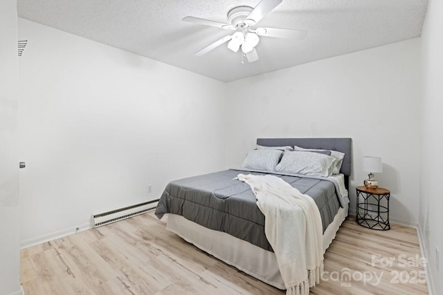 bedroom featuring wood finished floors, baseboard heating, ceiling fan, baseboards, and a textured ceiling
