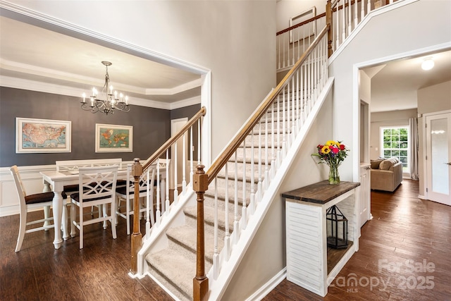 stairway with wood finished floors, a chandelier, crown molding, and baseboards