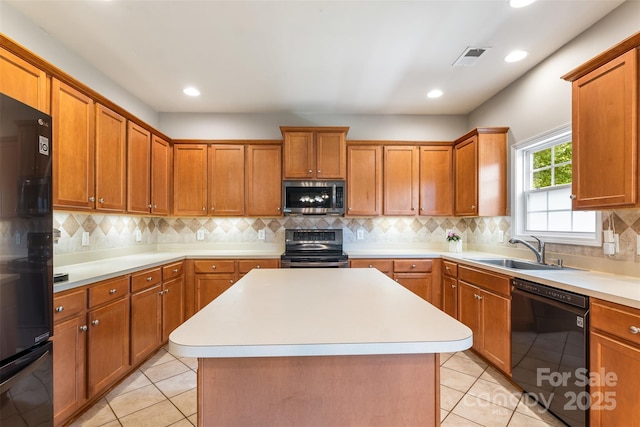 kitchen featuring black appliances, a sink, light countertops, brown cabinets, and backsplash