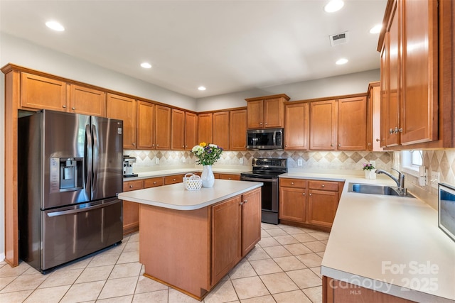 kitchen with stainless steel appliances, a sink, a kitchen island, light countertops, and brown cabinets