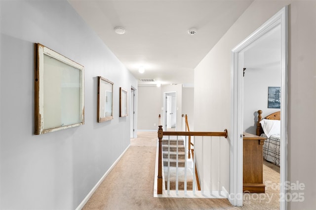hall with carpet floors, an upstairs landing, and baseboards