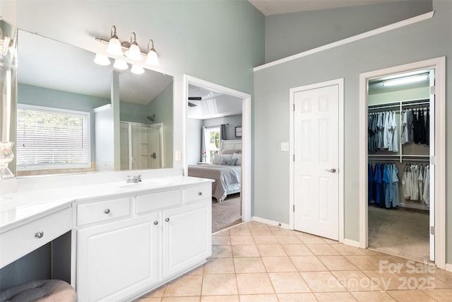 ensuite bathroom featuring tile patterned flooring, a stall shower, vanity, baseboards, and high vaulted ceiling