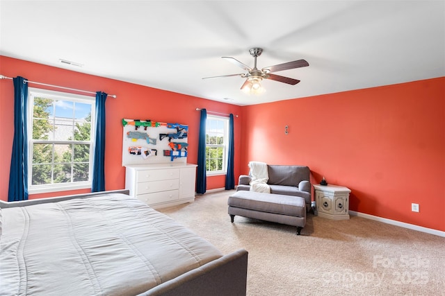 carpeted bedroom featuring multiple windows, a ceiling fan, and baseboards