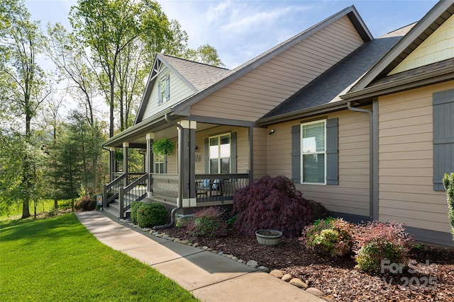 view of front of home featuring a porch, a shingled roof, and a front lawn