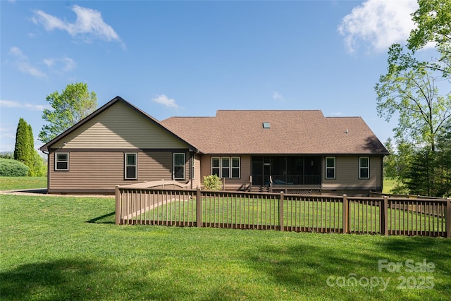 rear view of property with a lawn, roof with shingles, fence, and a sunroom
