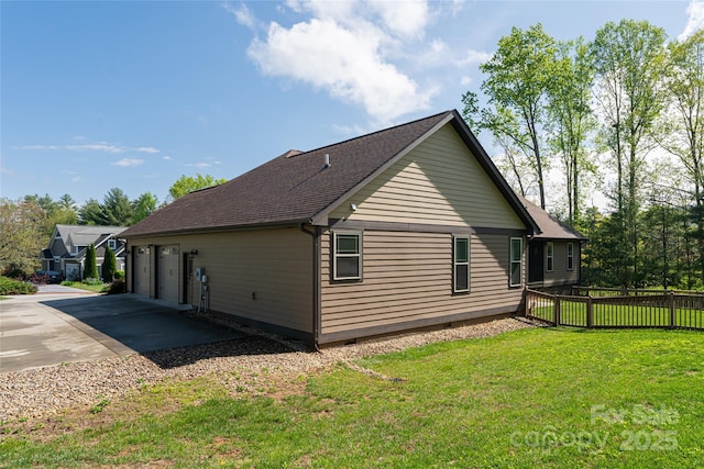 view of property exterior with a lawn, a shingled roof, fence, and a detached garage