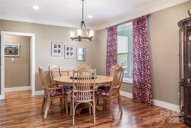 dining area featuring an inviting chandelier, ornamental molding, light wood finished floors, and baseboards