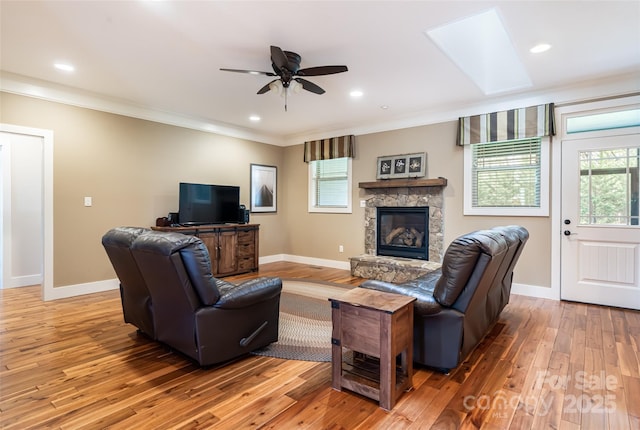 living area featuring crown molding, baseboards, light wood-type flooring, and a healthy amount of sunlight