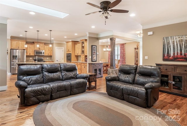 living room featuring a ceiling fan, decorative columns, ornamental molding, recessed lighting, and light wood-style flooring