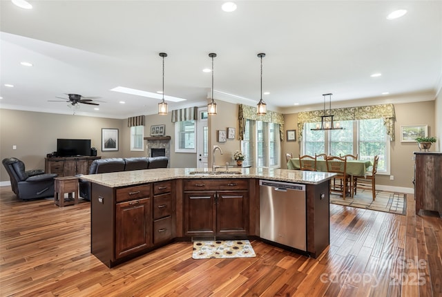 kitchen with stainless steel dishwasher, a ceiling fan, crown molding, wood finished floors, and a sink