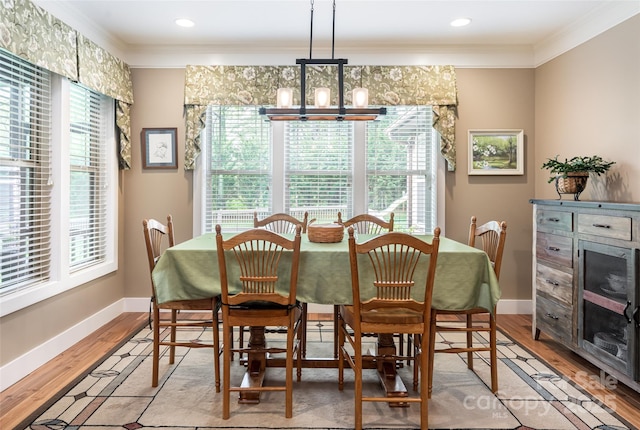 dining space featuring crown molding, baseboards, a chandelier, and light wood finished floors