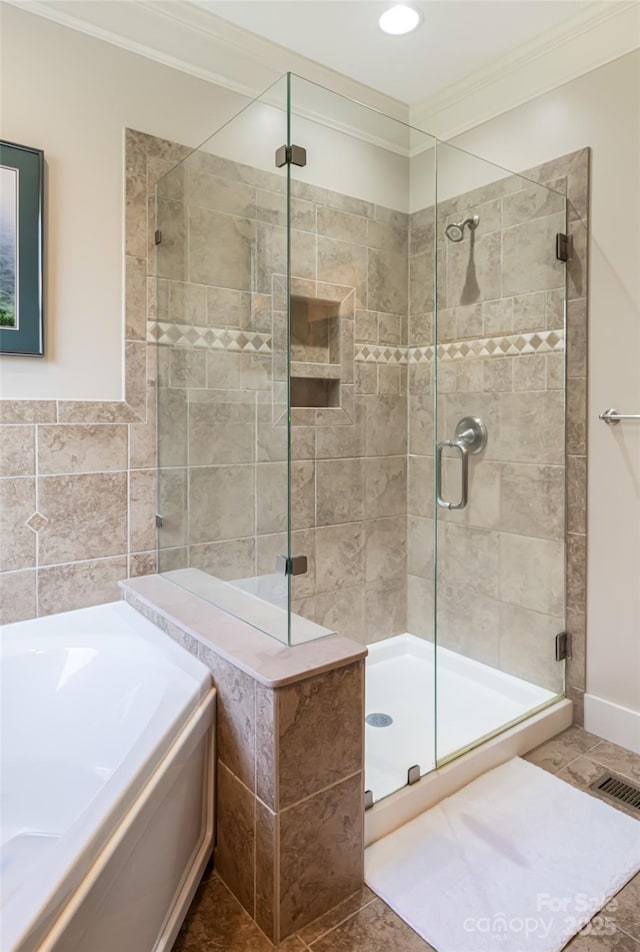bathroom featuring visible vents, ornamental molding, baseboards, a bath, and a shower stall