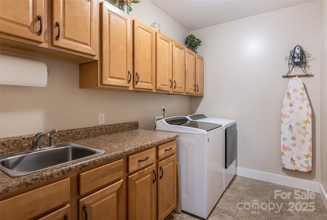 laundry room featuring baseboards, a sink, cabinet space, and washing machine and clothes dryer