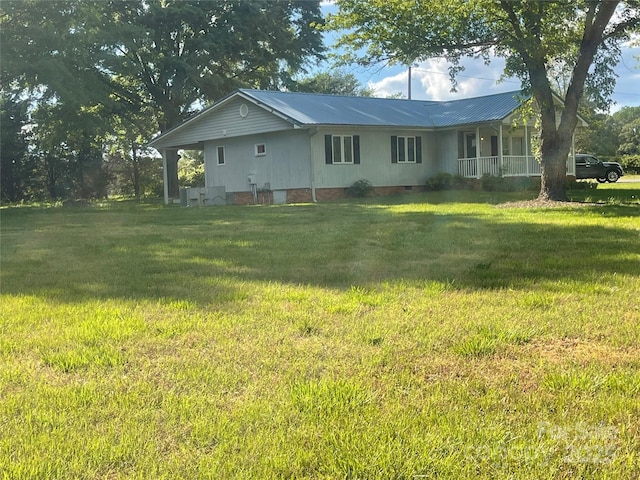 rear view of property with crawl space, metal roof, and a lawn