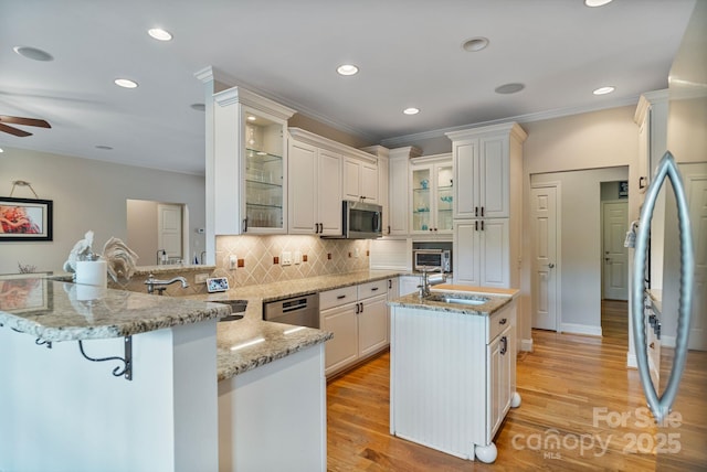 7471 Barfield Ln, Denver, NC 28037 - kitchen featuring appliances with stainless steel finishes, a peninsula, a sink, ornamental molding, and an island with sink