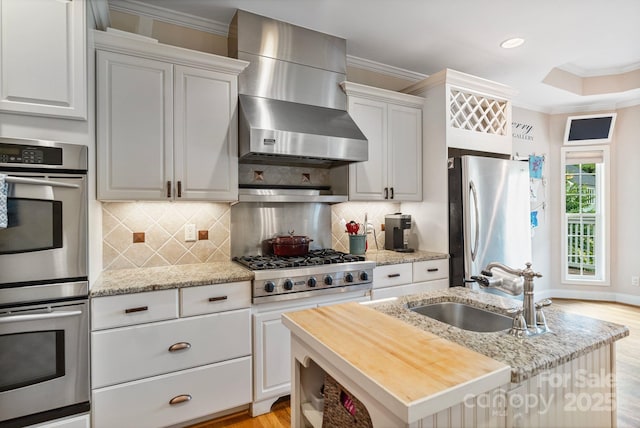 7471 Barfield Ln, Denver, NC 28037 - kitchen with appliances with stainless steel finishes, a sink, wall chimney range hood, a center island with sink, and crown molding