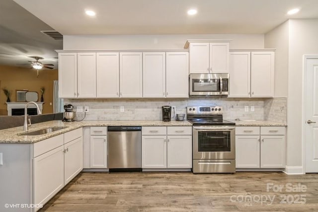 876 Hardin St Unit B24, Lancaster, SC 29720 - kitchen with appliances with stainless steel finishes, a sink, white cabinets, a peninsula, and light wood-style floors