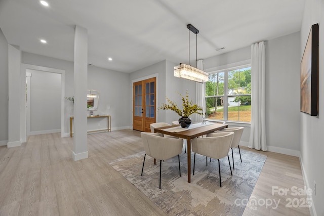 dining area featuring french doors, light wood finished floors, and baseboards
