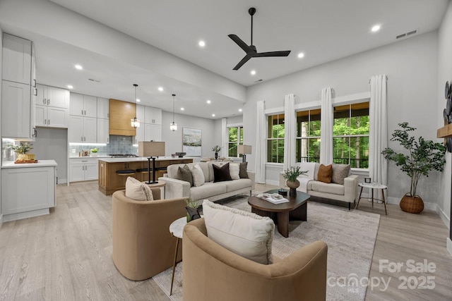 living area with visible vents, light wood-type flooring, a ceiling fan, and recessed lighting