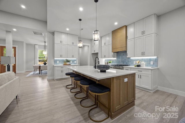 kitchen featuring baseboards, visible vents, light countertops, and decorative backsplash