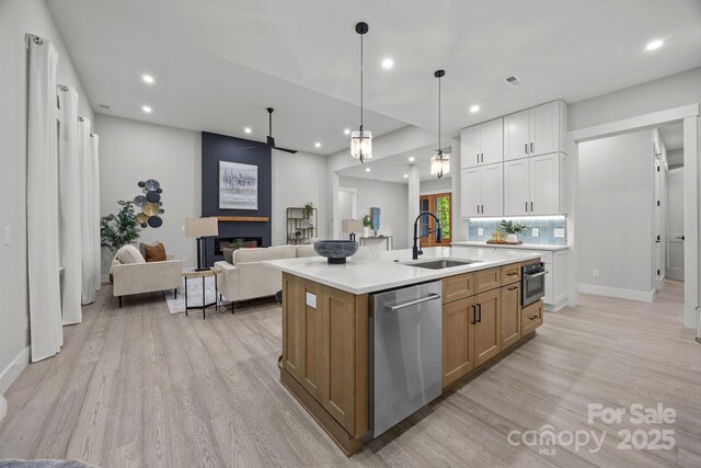 kitchen with stainless steel appliances, open floor plan, light wood-style flooring, and a sink